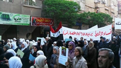 Женщины несут плакат с надписью «Женщины Дарайя хотят прекращения осады» в апреле 2011 года