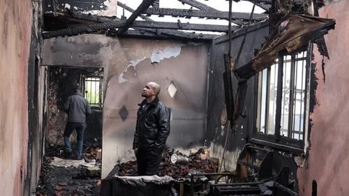 Палестинец осматривает остатки своего сгоревшего дома в Фандакумии.