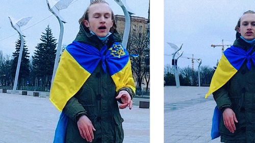 Художественная акция Давида: он поет гимн Украины на Площади Свободы в Мариуполе c характерными уличными фонарями в форме голубей на заднем плане