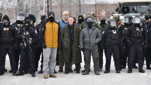 Грегори Бовино (в центре) стоит в окружении других федеральных агентов во время протеста против ICE