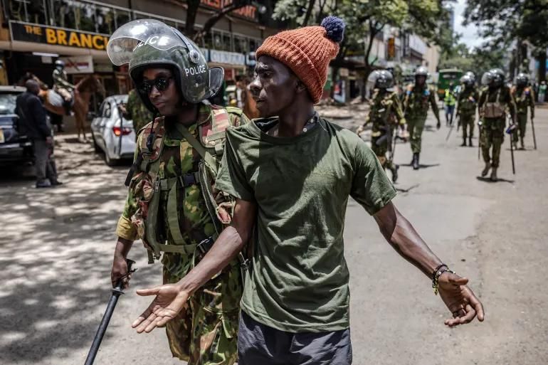 Полицейский арестовывает протестующего в Найроби.
