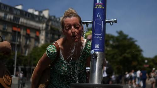 Женщина охлаждается в общественном фонтане возле площади Трокадеро во время сильной жары в Париже